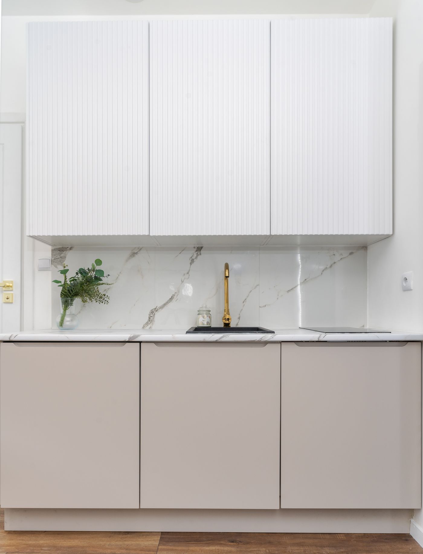 Cream kitchen with marble backsplash and gold faucet